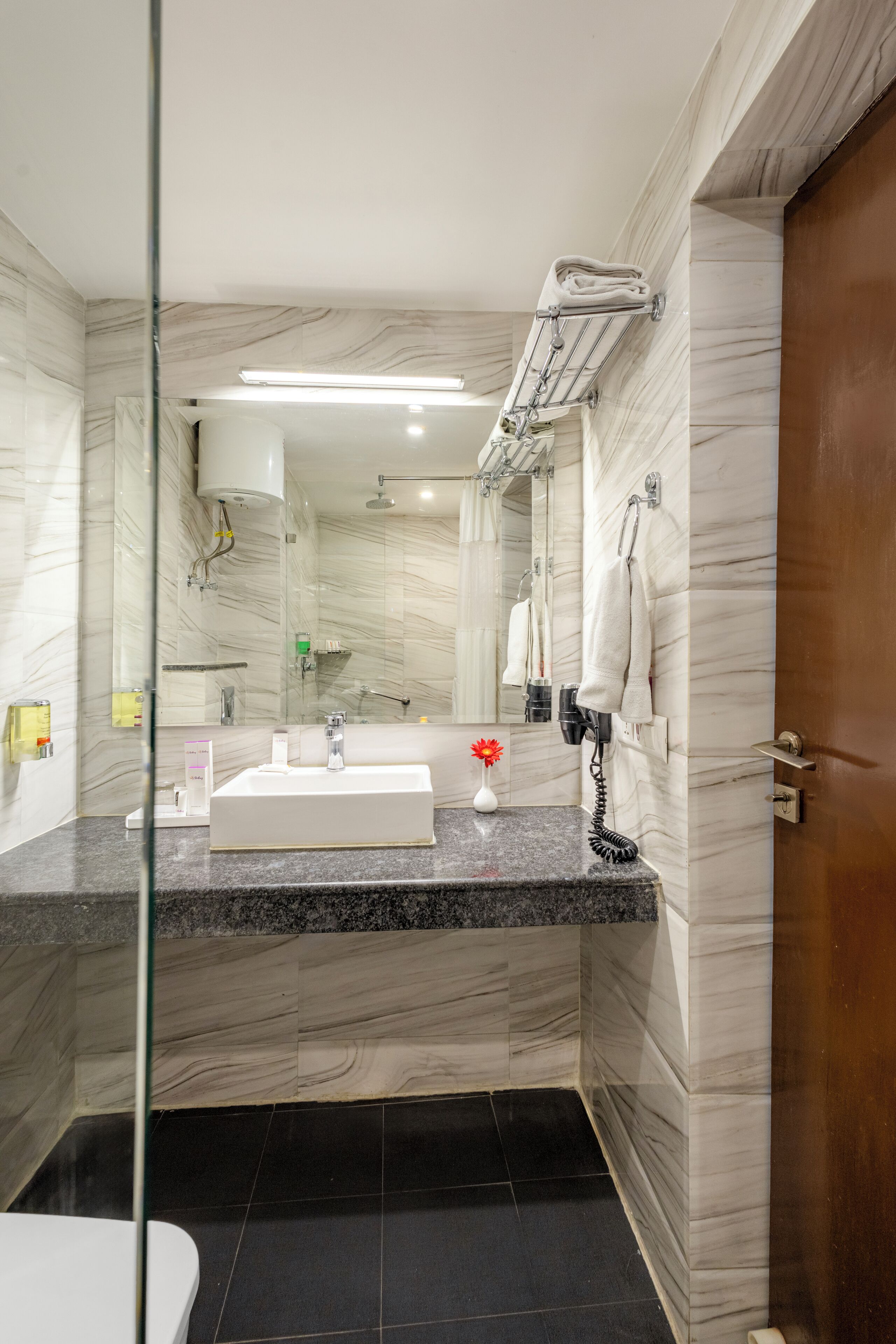 A modern bathroom with a marble vanity, a glass shower enclosure, and a towel rack.