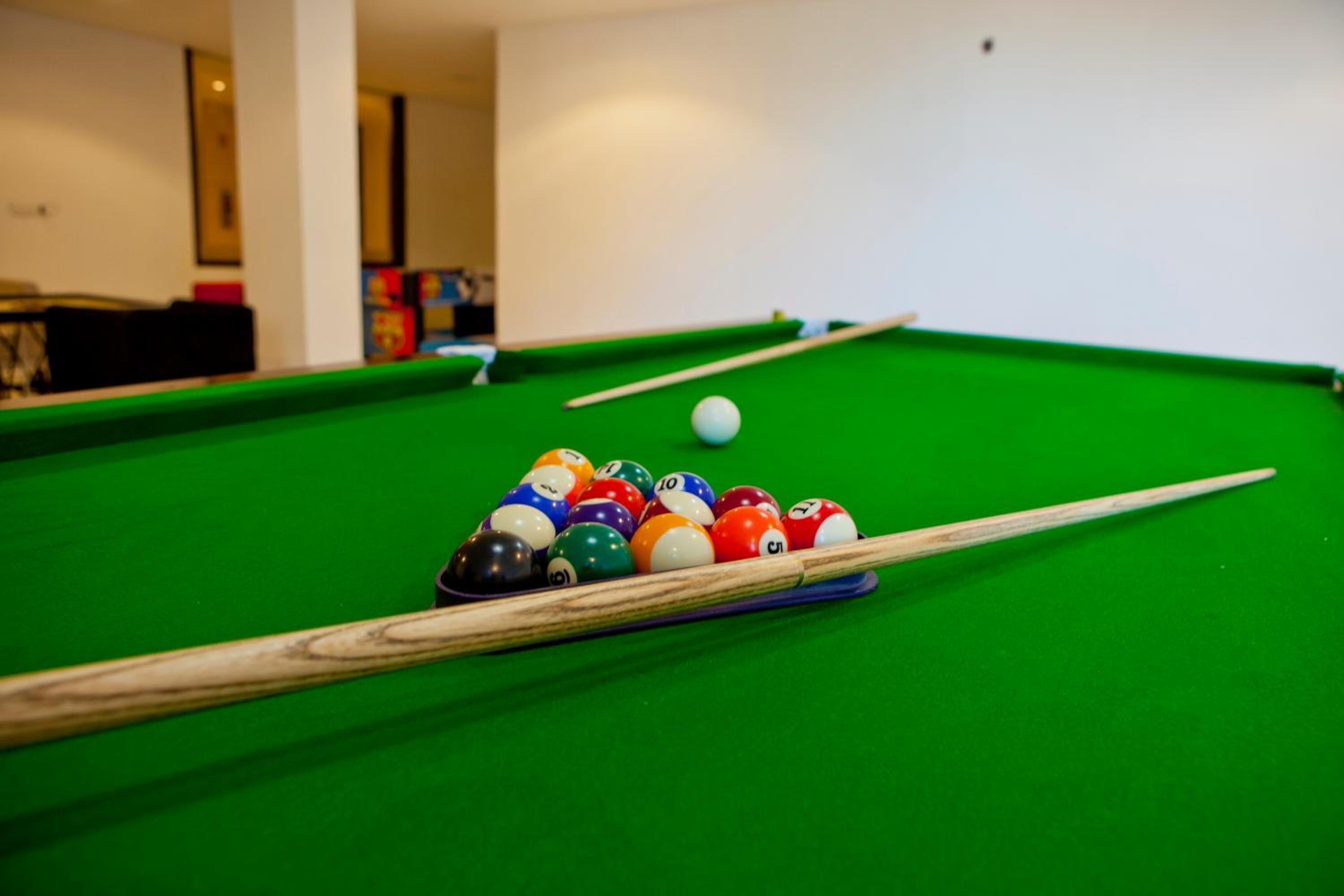 A pool table with a set of billiard balls and cues.
