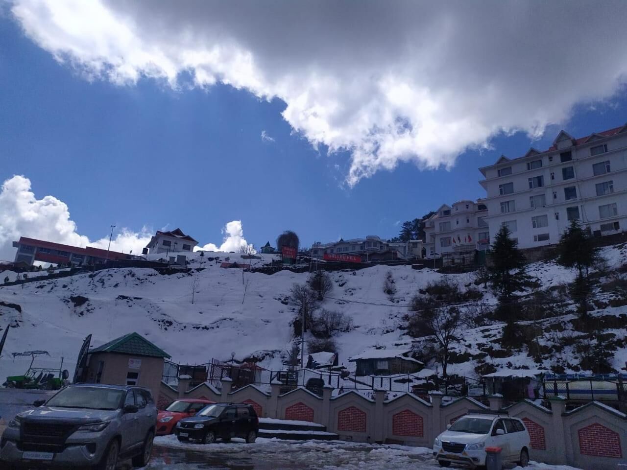 A snowy landscape with buildings and parked cars.