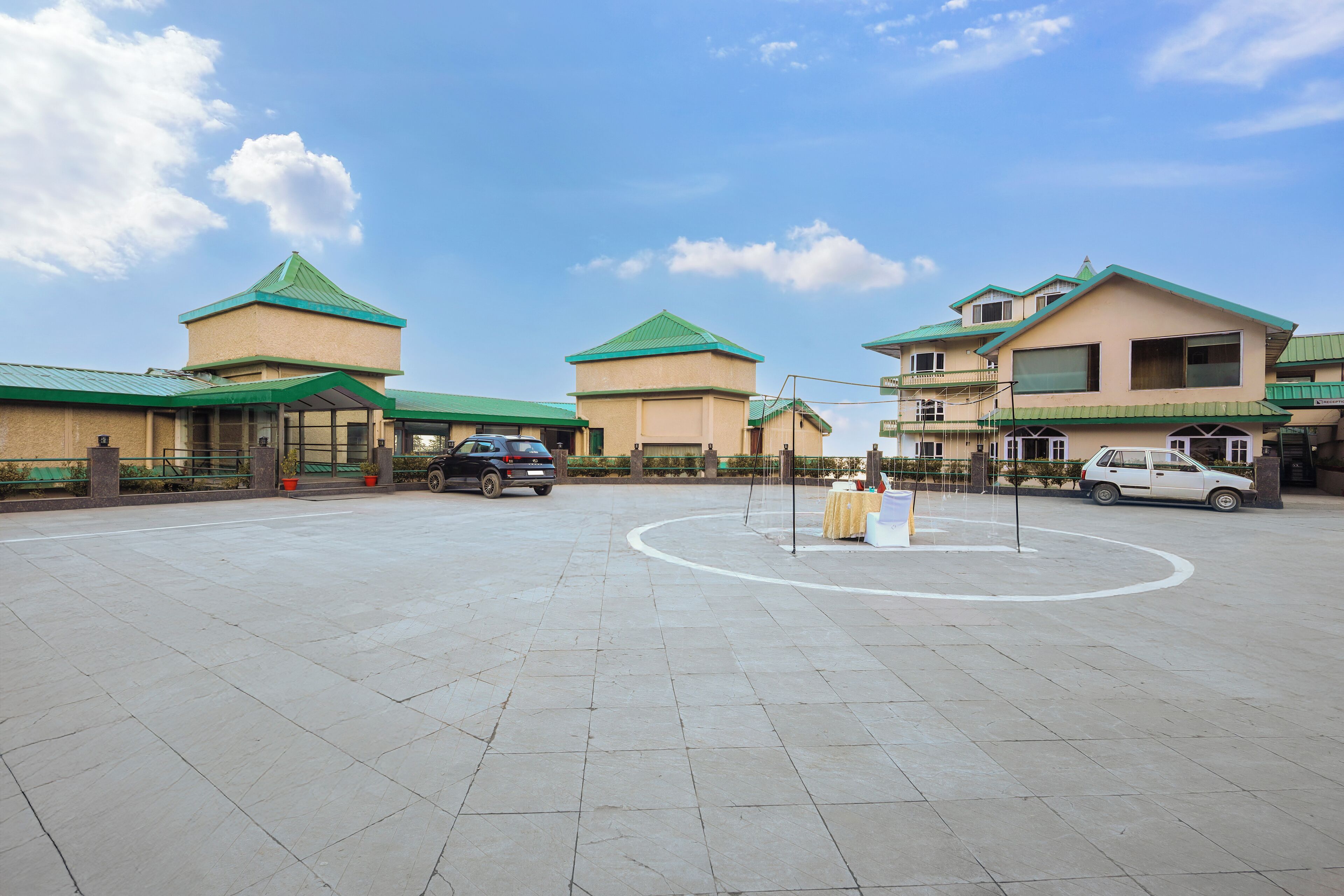 A spacious outdoor area with a circular walkway, surrounded by buildings with green roofs and beige walls.