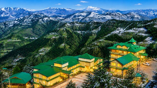 A hotel with multiple buildings, green roofs, and a mountainous backdrop. - Sterling Kufri (Theog)