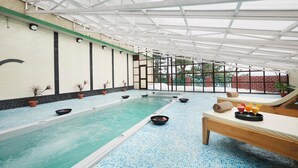 An indoor swimming pool with a tiled floor, benches, and potted plants. - Sterling Kufri (Theog)