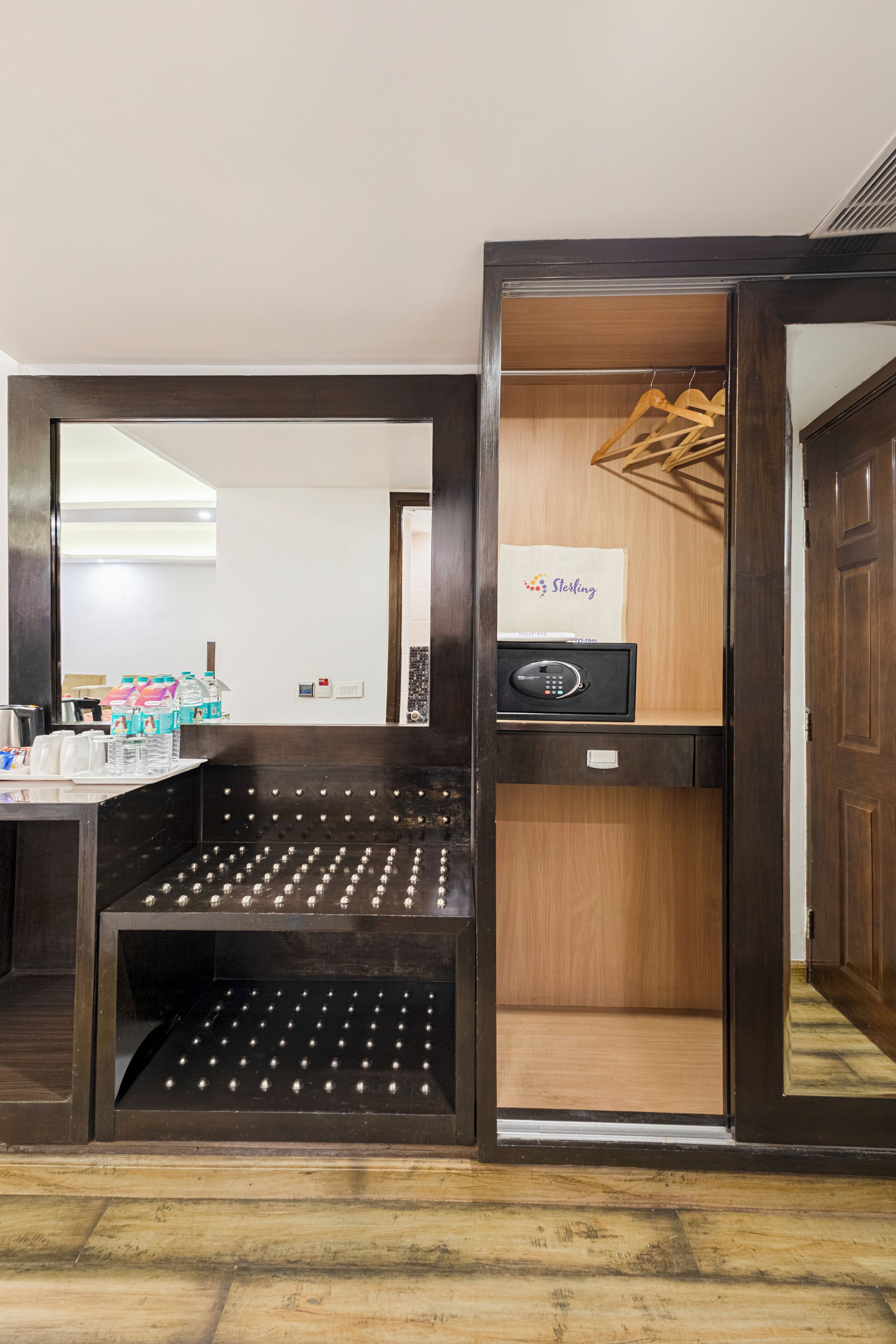Une chambre d’hôtel avec une armoire en bois, un mini-bar et un miroir.