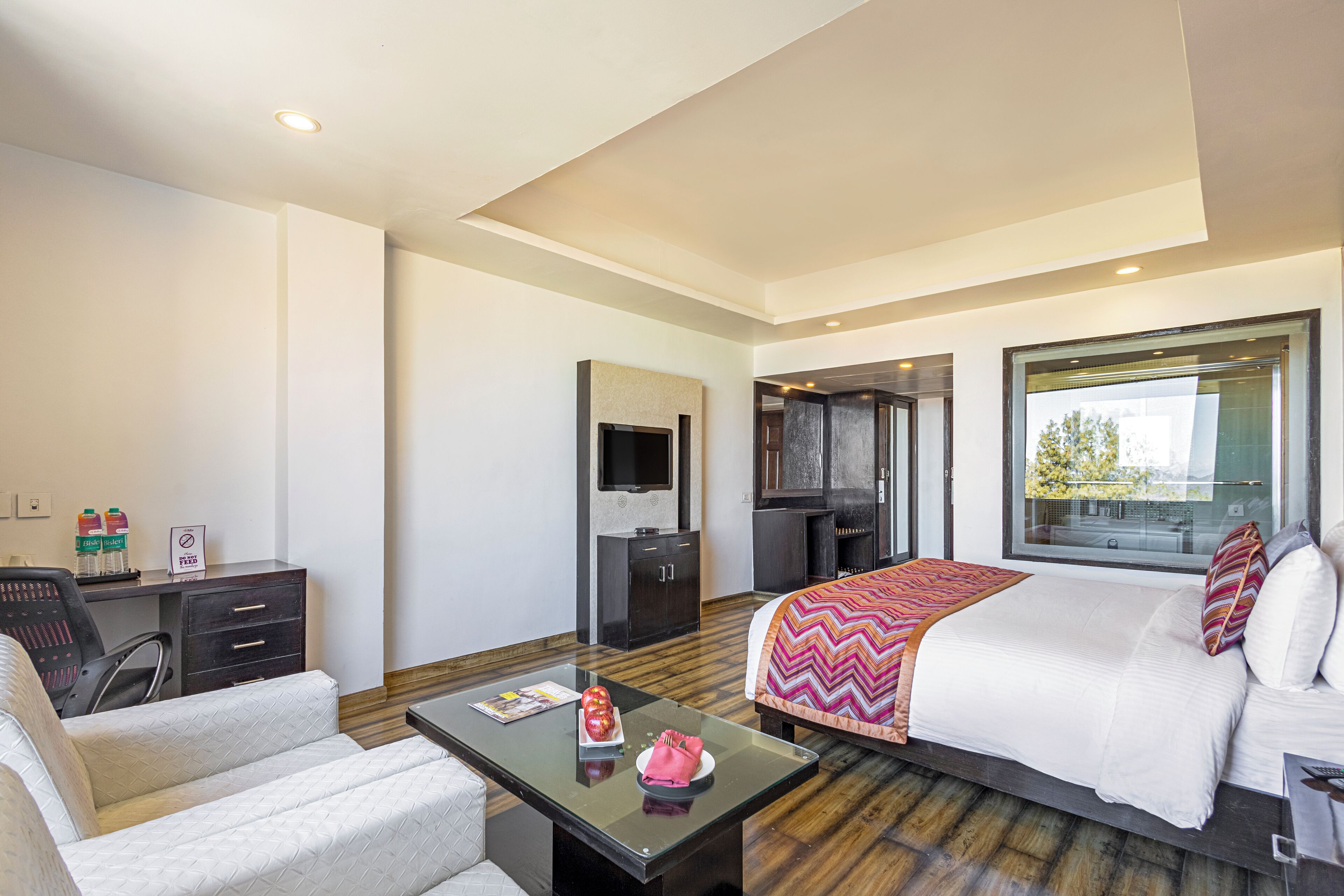Une chambre d’hôtel avec un lit, un bureau, une chaise, une télévision et une fenêtre.