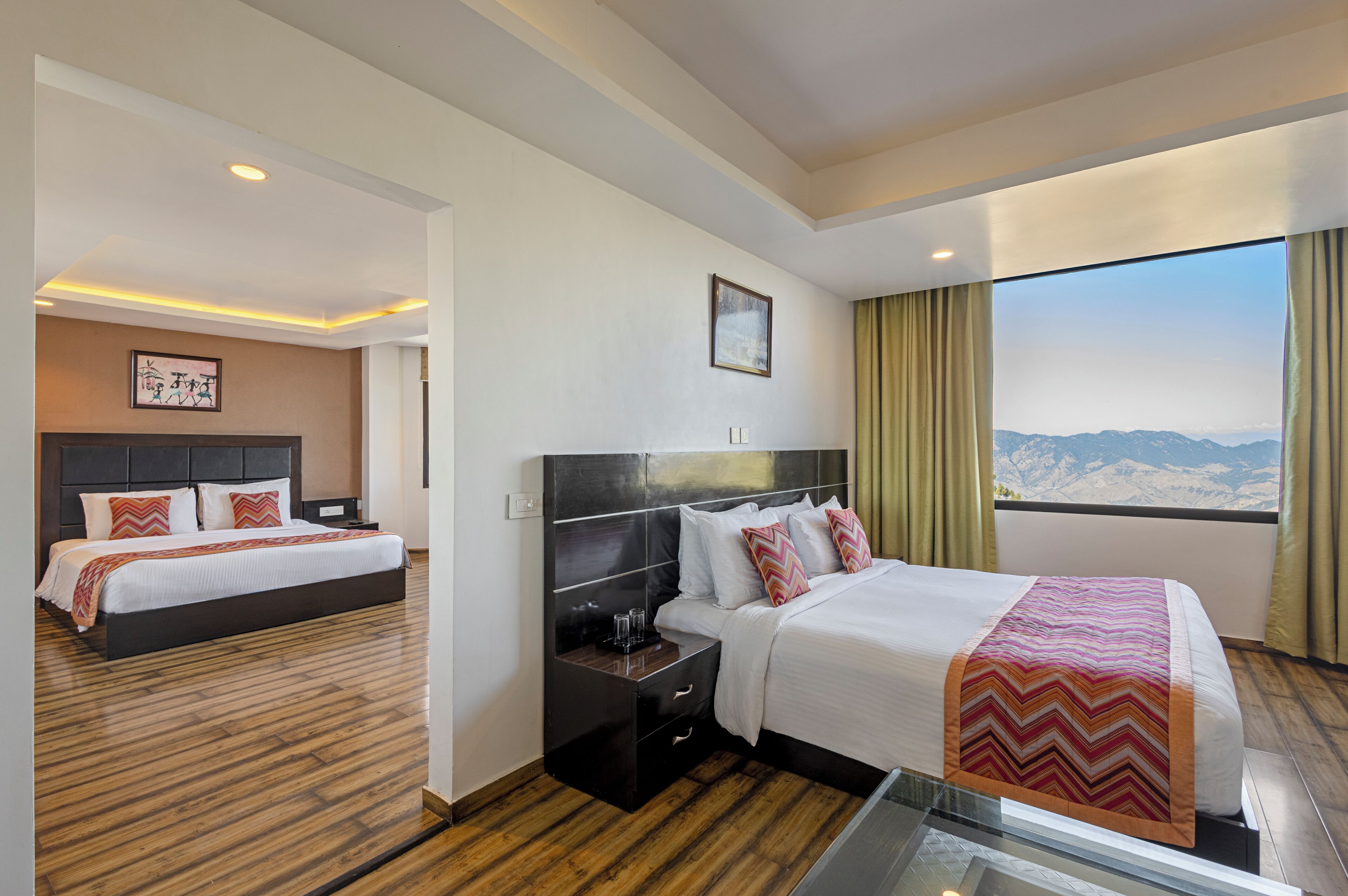 Habitación de hotel con dos camas, un ventanal con vistas a la montaña, un cuadro en la pared y un diseño moderno.