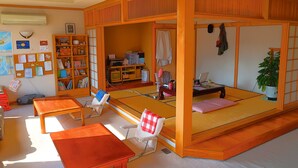 A traditional Japanese-style room with tatami flooring, a low wooden bed frame, a desk with a chair, a bookshelf, and a potted plant. - Otaru Ekimae Guest House Ito - Hostel (Otaru)