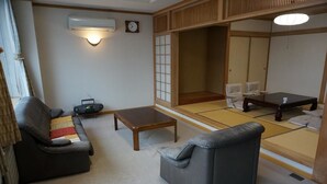 A traditional Japanese room with tatami flooring, a sofa, a coffee table, and a low table. - Otaru Ekimae Guest House Ito - Hostel (Otaru)