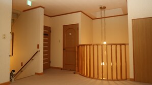 A hallway with a wooden staircase, a door labeled "2", and a wooden railing. - Otaru Ekimae Guest House Ito - Hostel (Otaru)