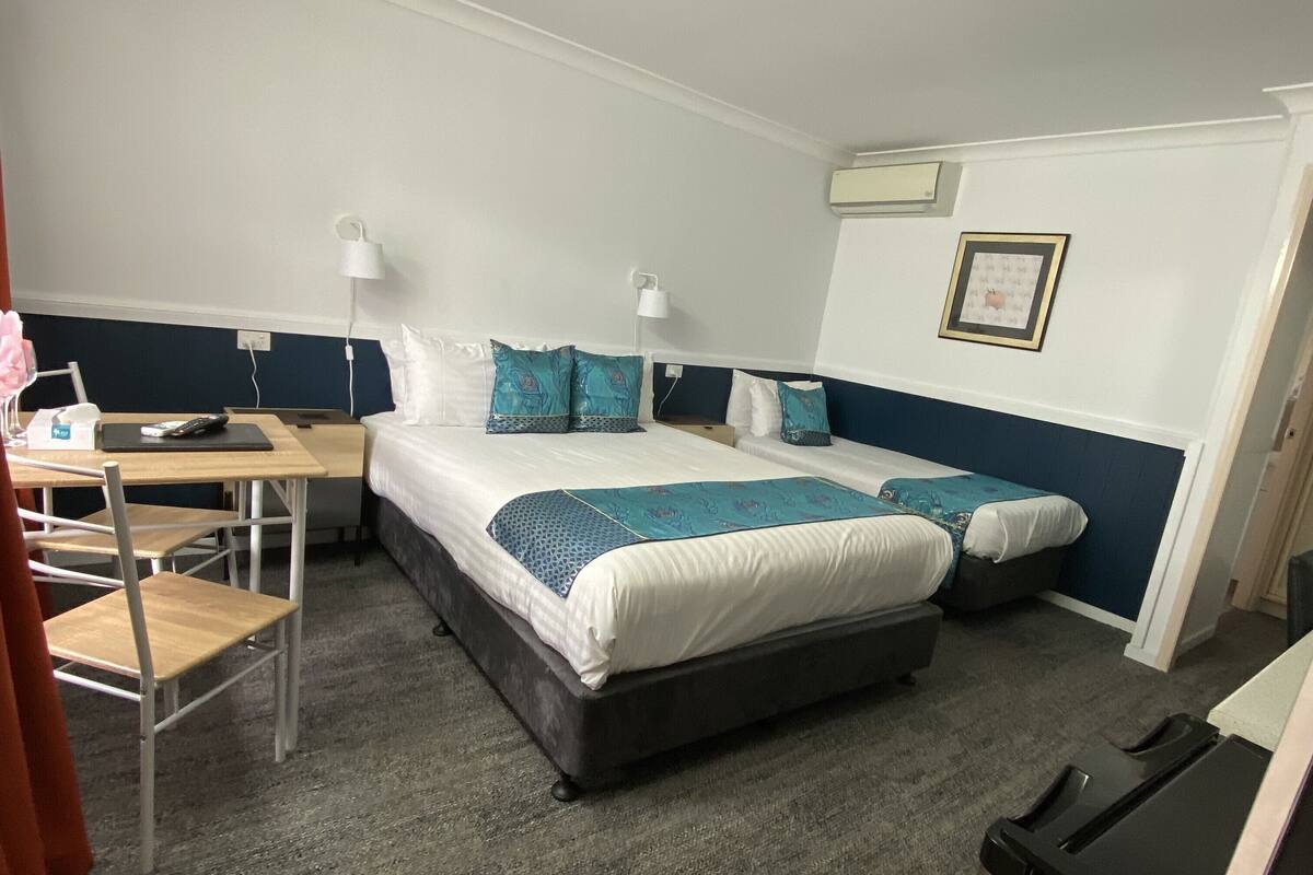 A hotel room with two beds, a desk, a chair, and a TV.