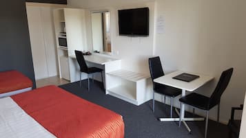 A hotel room with a bed, a desk with a chair, a TV, and a wardrobe.