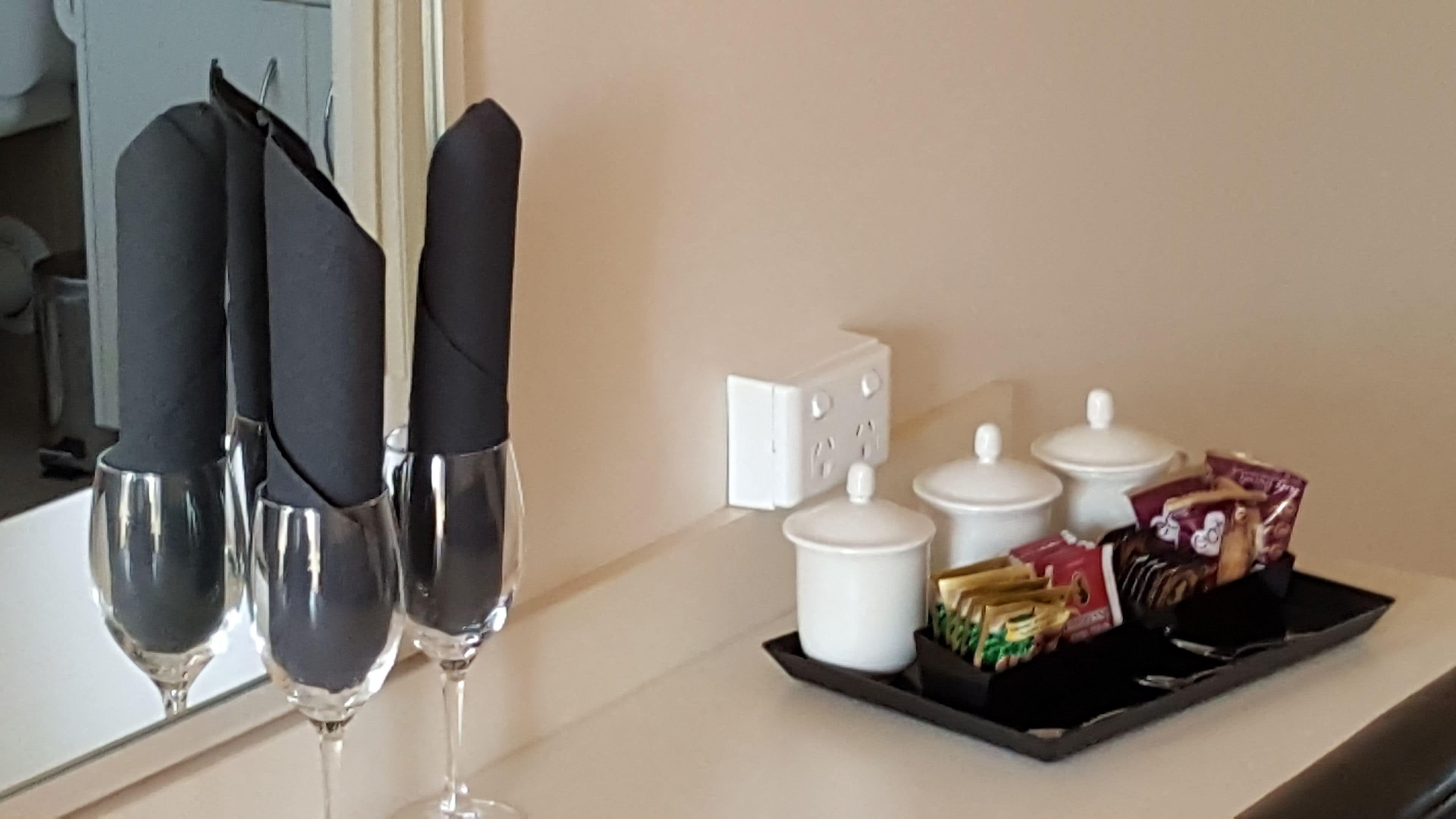 A hotel room with a minibar, a tray with snacks, and two glasses of water.