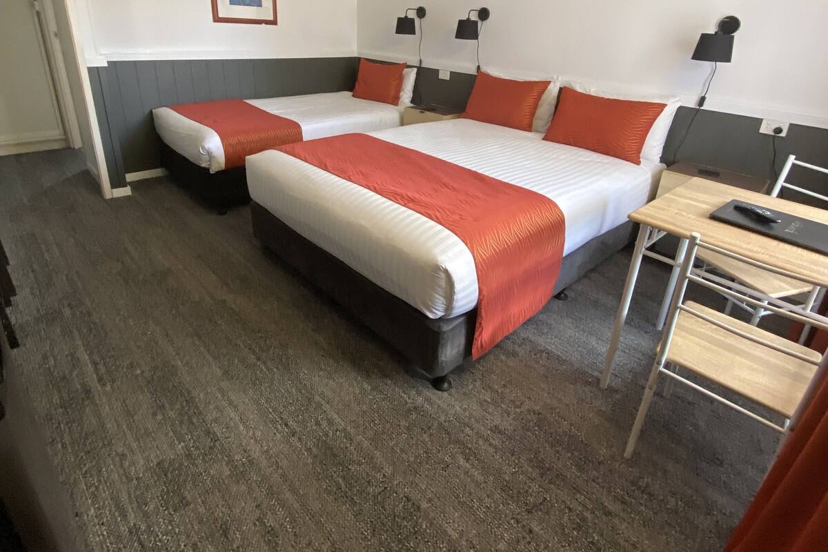 A hotel room with two beds, a desk, and a chair.