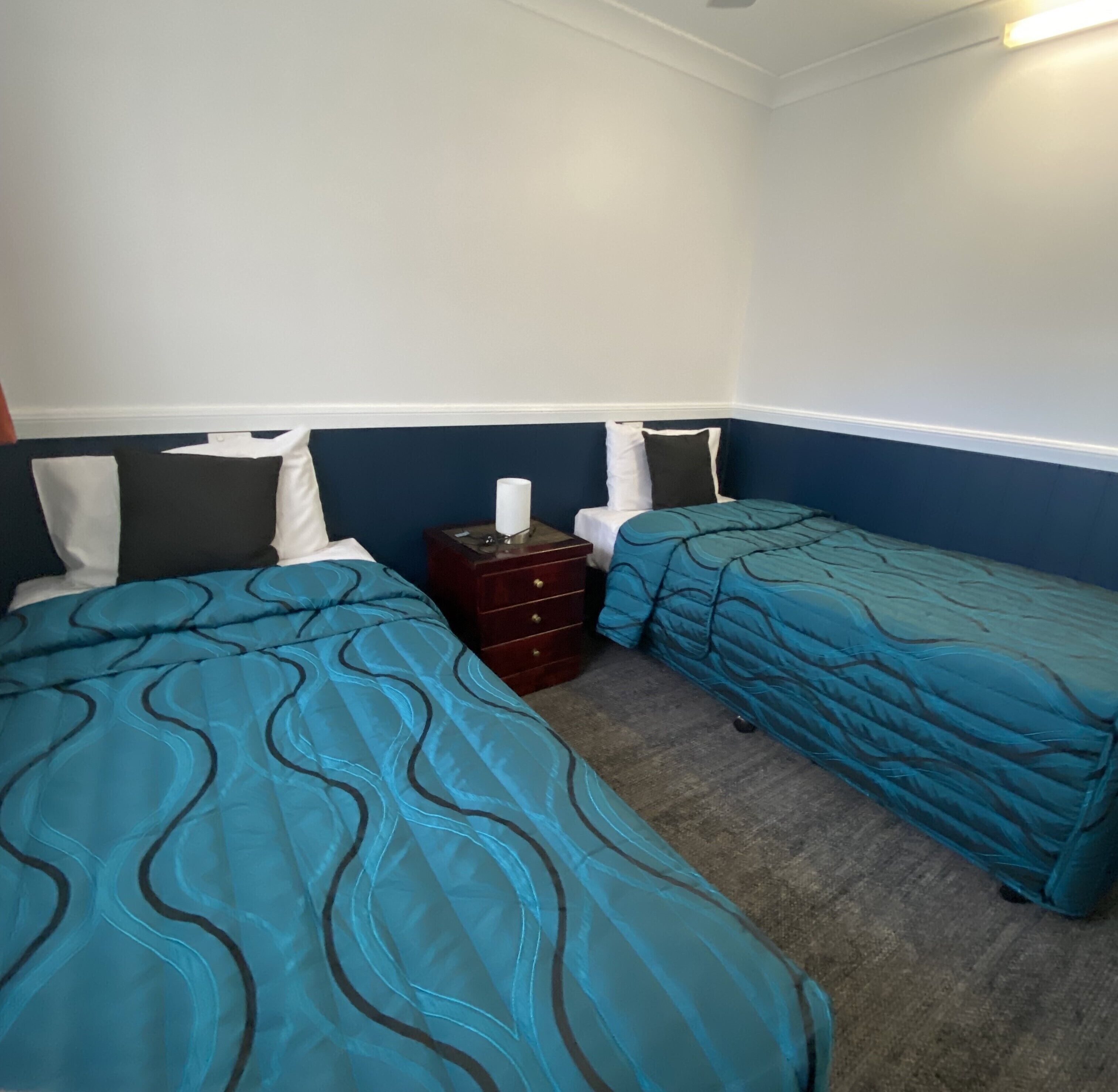 A room with two beds, a dresser, and a nightstand.