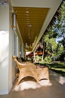 A covered outdoor seating area with wicker furniture and a thatched roof structure.