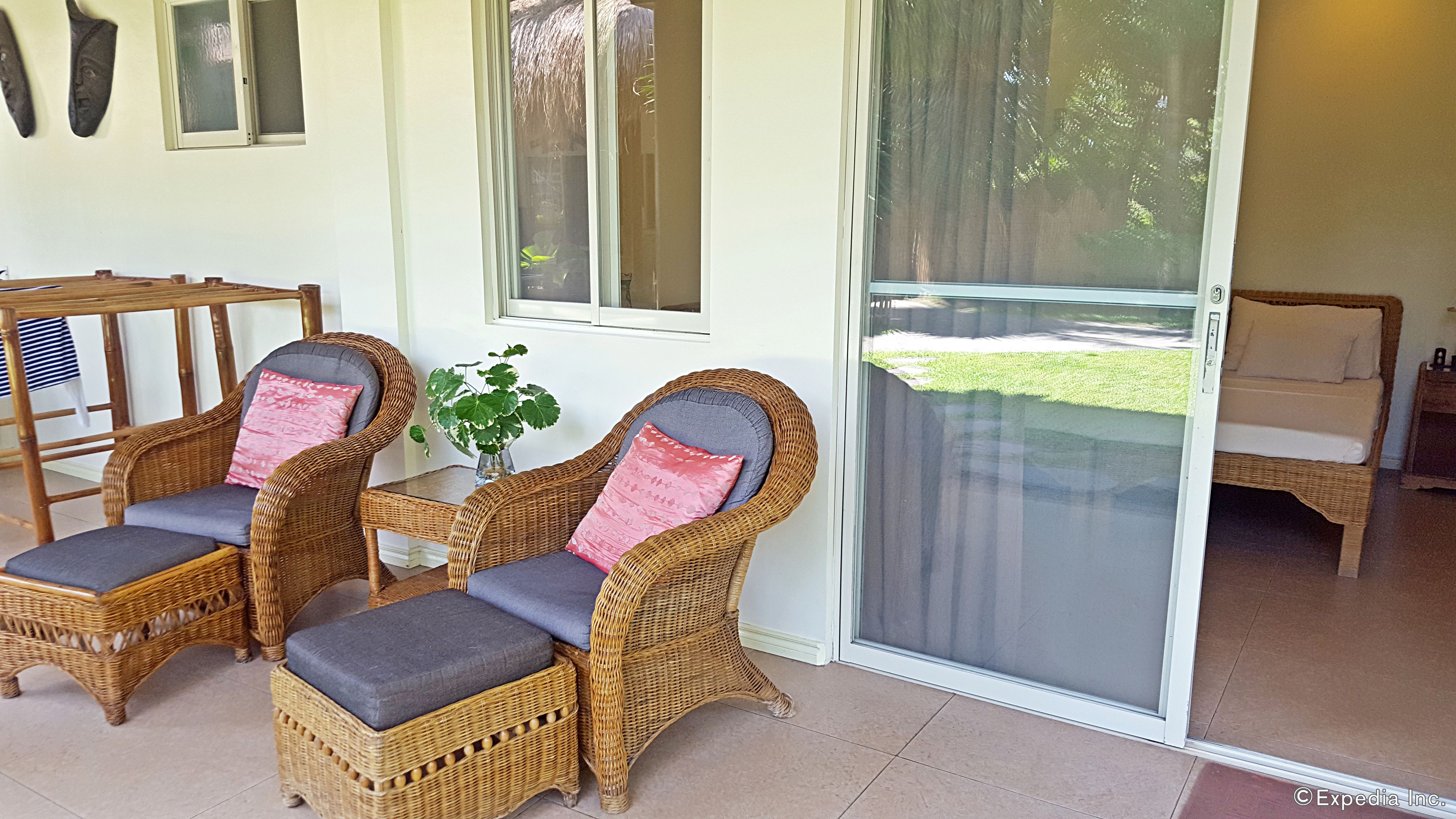 A room with wicker furniture, including two chairs and a small table with a vase.
