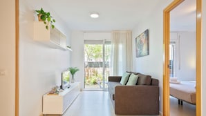 A modern living room with a sofa, a TV, and a plant.