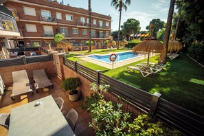 Una piscina al aire libre, sombrillas, sillones reclinables de piscina