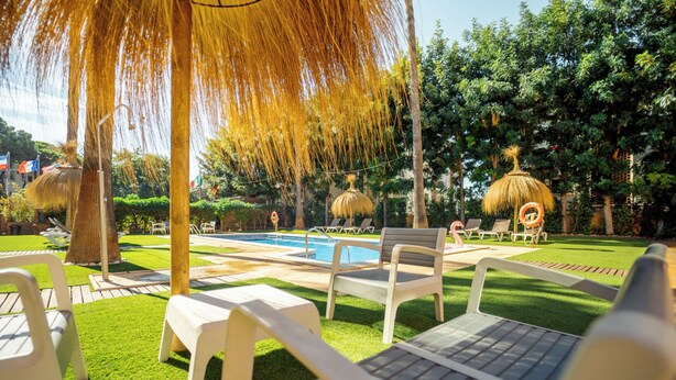A poolside area with lounge chairs, a swimming pool, and thatched umbrellas.