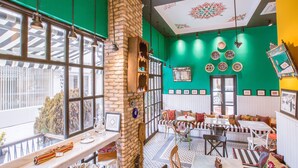 A restaurant with a brick fireplace, large windows, and a green and white color scheme.