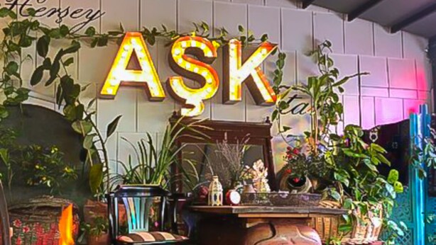 A cozy room with a fireplace, a vintage radio, and a sign that reads "ASK".