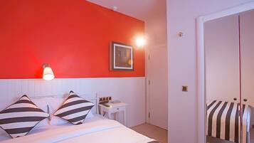 A hotel room with a bed, a bedside table, a lamp, a framed picture, and a wardrobe.