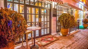 A hotel entrance with a checkered awning, a glass door, and a red carpet leading to the entrance.