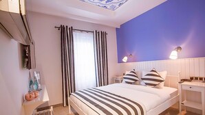 A bedroom with a bed, a nightstand, a lamp, a chair, and a window with curtains.