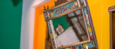 A mirror with a decorative frame against a wall with a green and yellow color scheme.