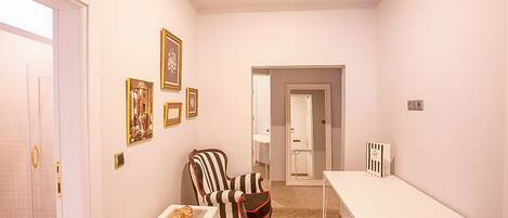 Una habitación con una puerta blanca, una silla a rayas, una mesita pequeña y una mesa blanca.