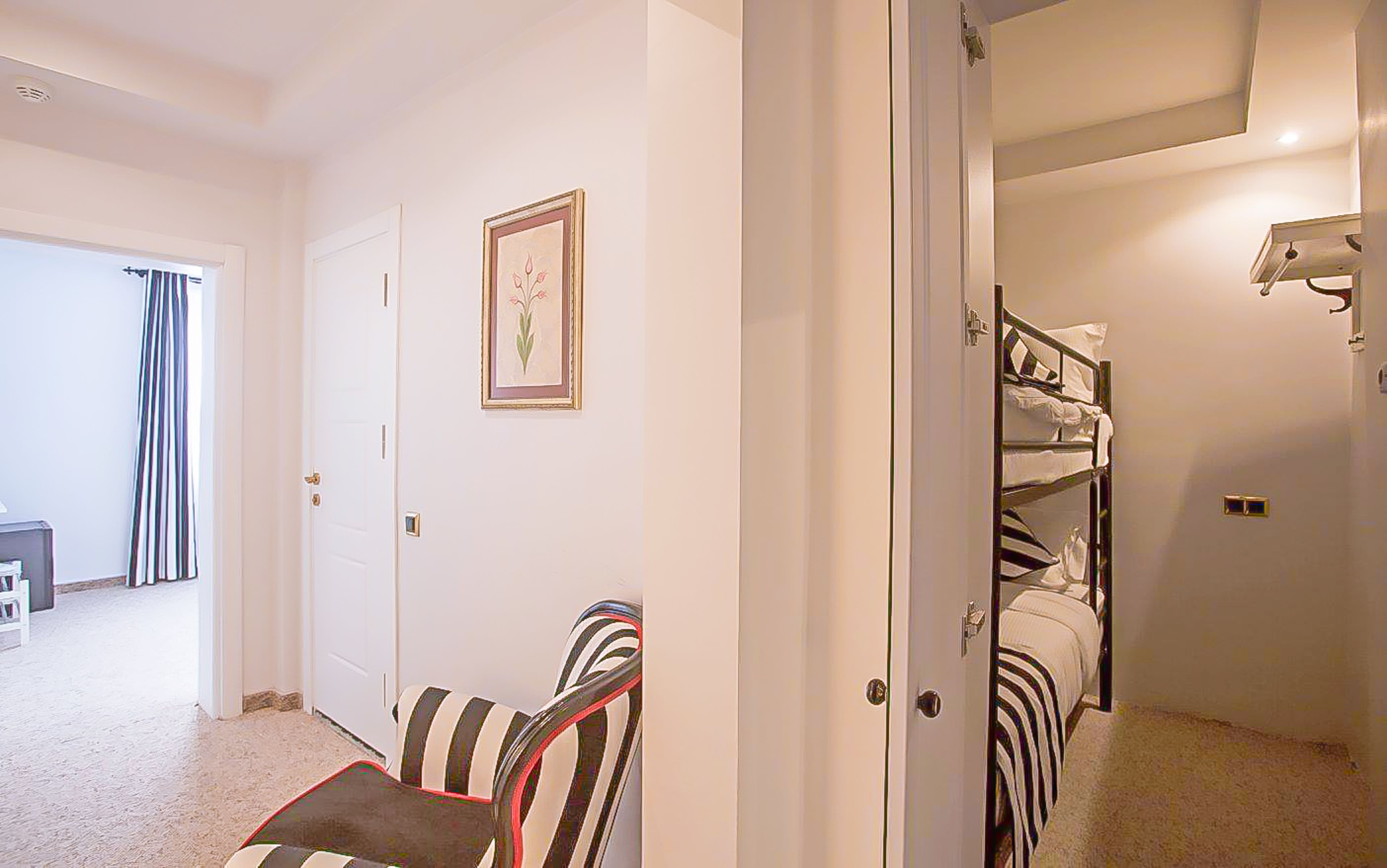 A hotel room with a bed, a chair, a door, and a framed picture on the wall.