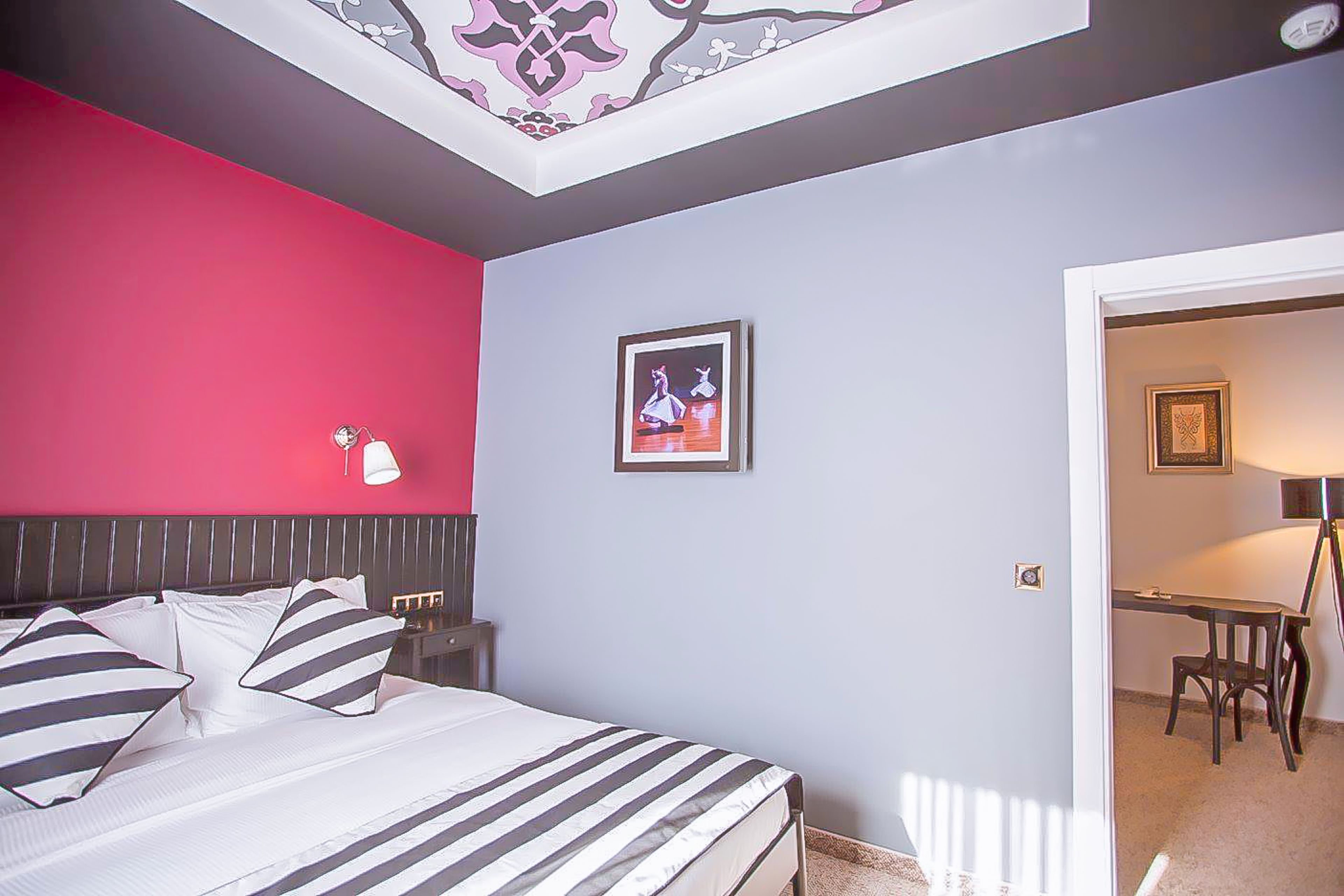 A bedroom with a bed, a nightstand, a framed picture, and a desk with a chair.
