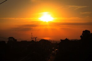 A sunset over a residential area with houses and a road. - Guru Ratna Homestay (Munduk)