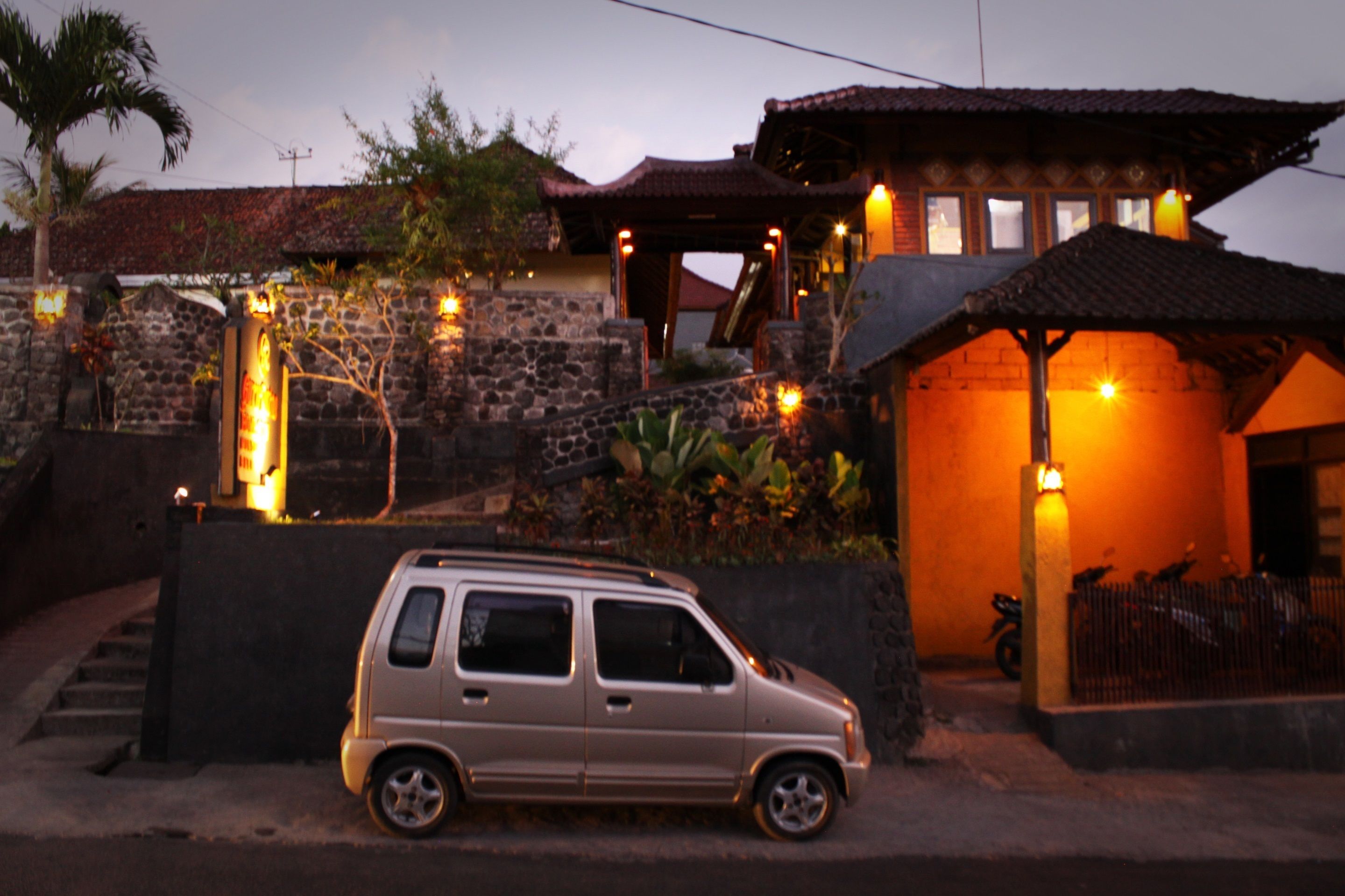 Un edificio con fachada de piedra, estructura de madera y techo de tejas, y un coche estacionado al frente.