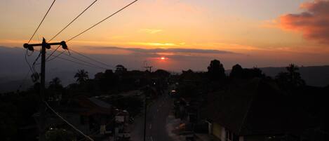 A street view at sunset with houses and power lines.