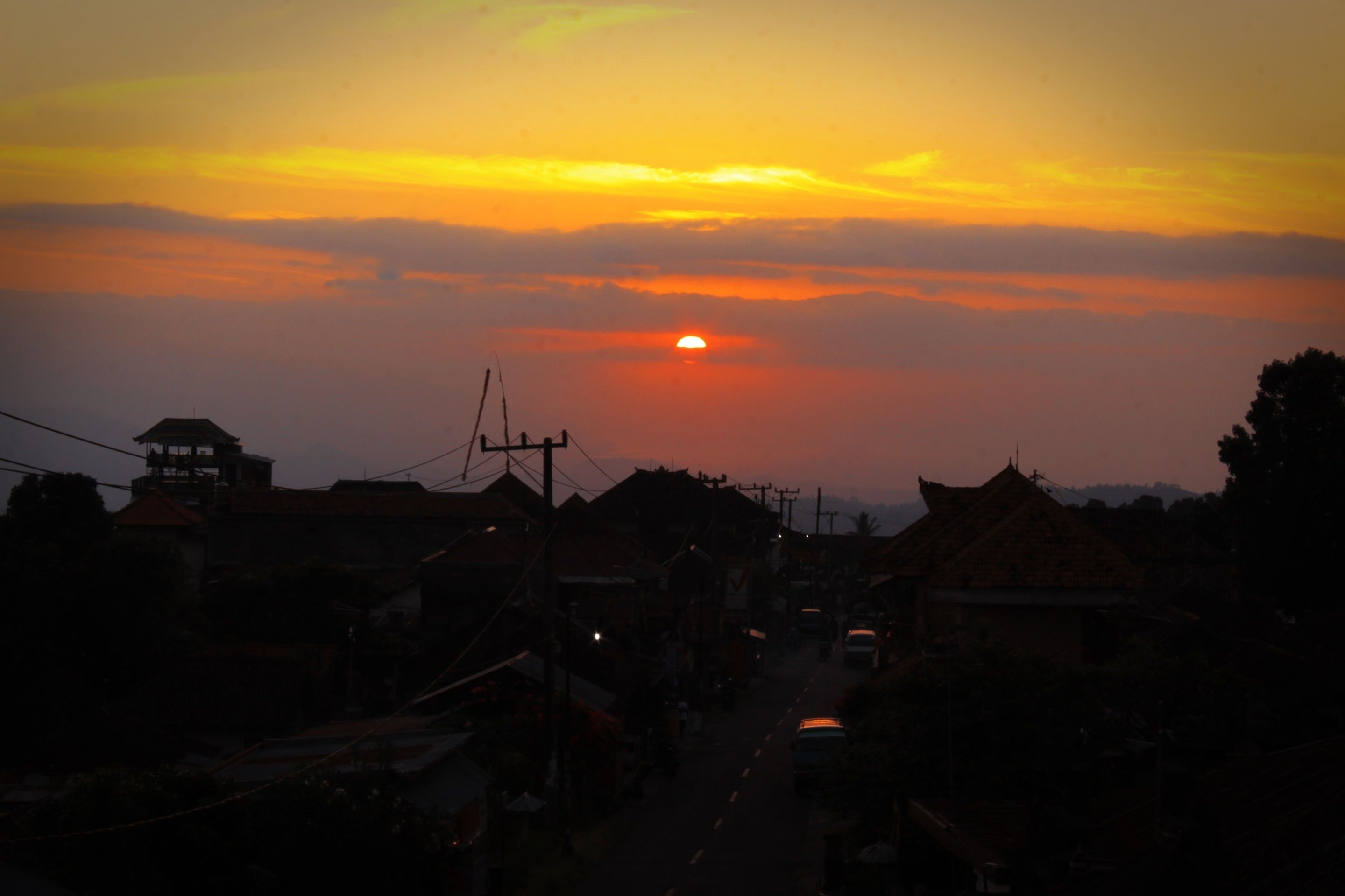 A street at sunset with buildings and a clear sky.
