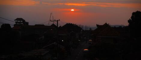 A street at sunset with buildings and a clear sky.