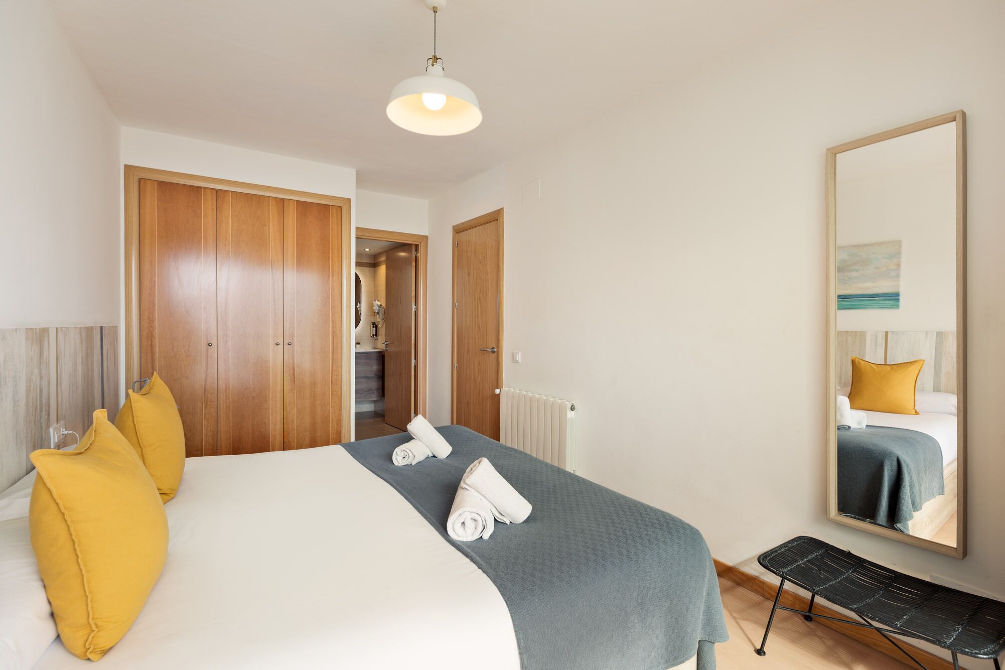 Een hotelkamer met een bed, een spiegel, een radiator en een bank.