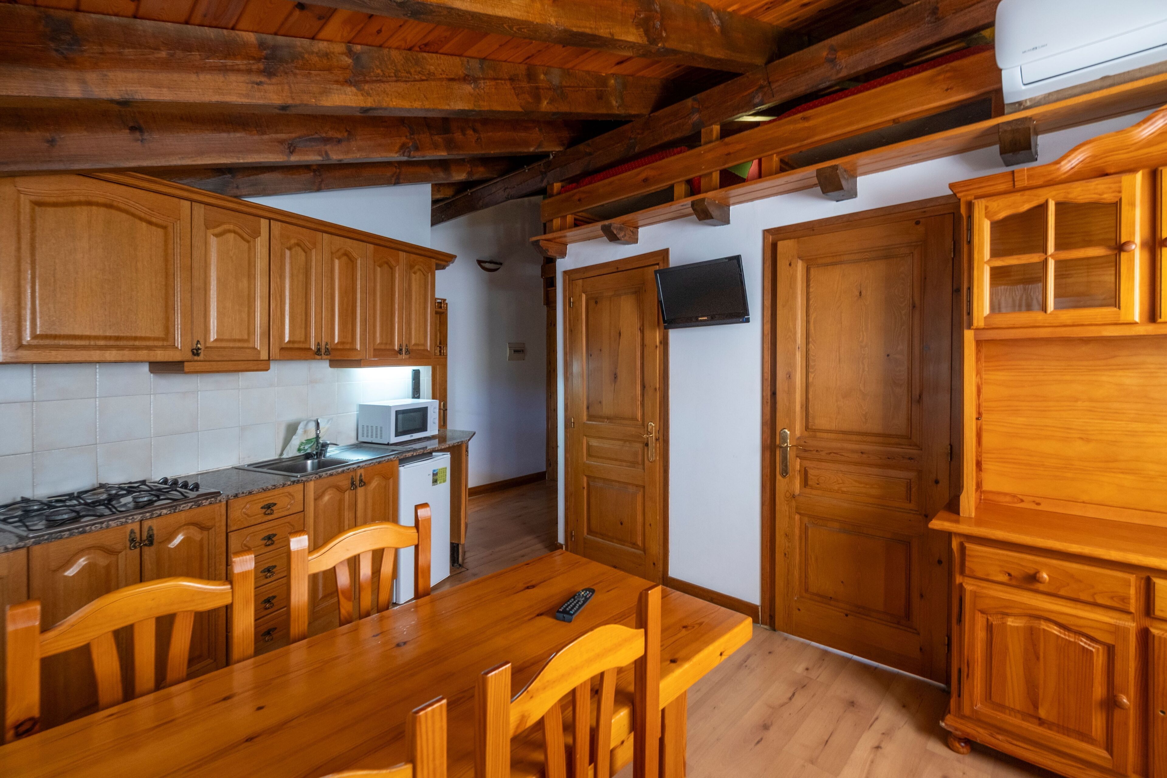 A kitchen with wooden cabinets, a dining table, chairs, a microwave, and a stove.