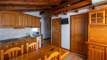 A kitchen with wooden cabinets, a dining table, chairs, a microwave, and a stove.