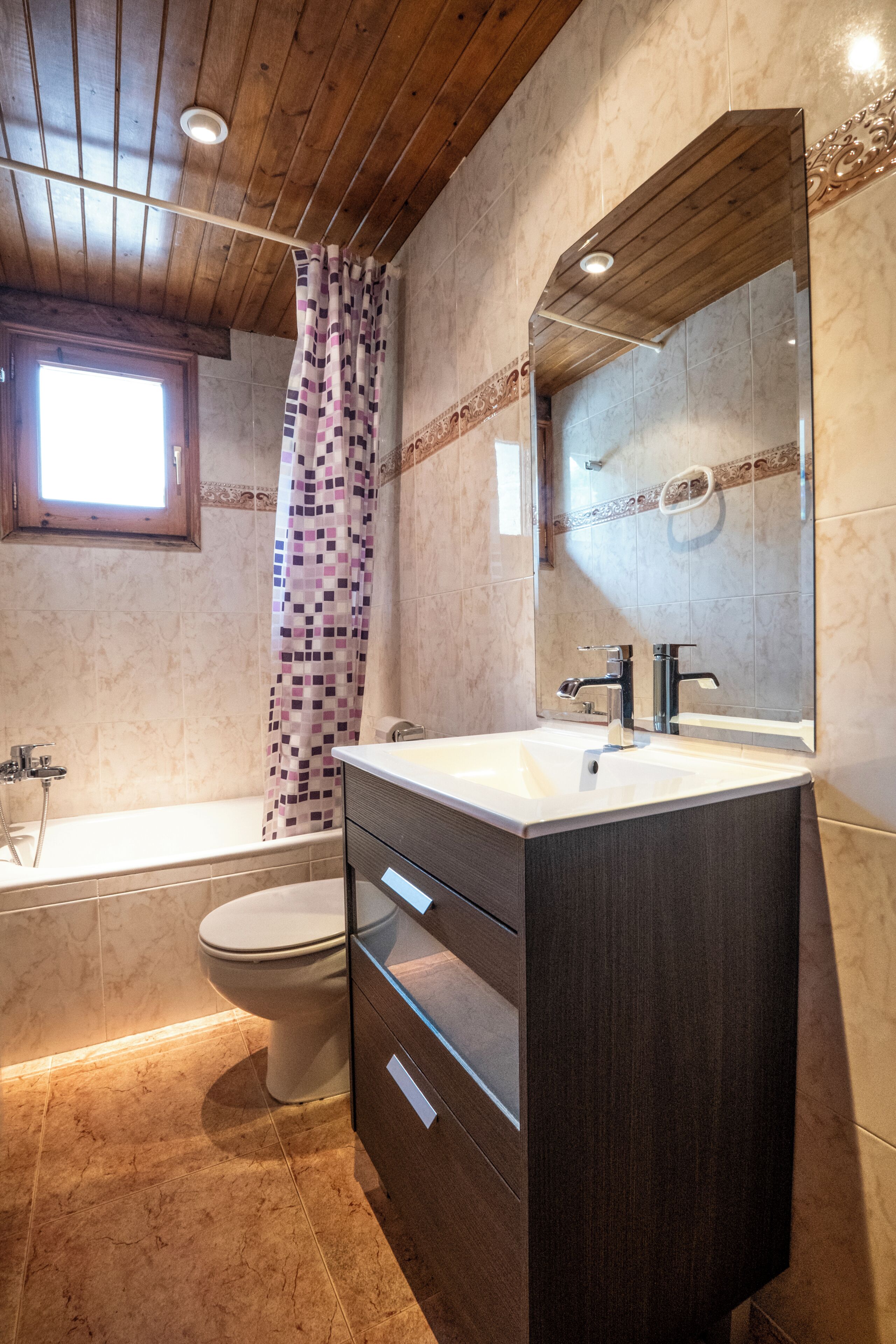 A bathroom with a bathtub, toilet, vanity with drawers, and a large mirror.