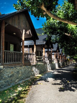 Une rangée de cabanes en bois aux murs de pierre, avec des balustrades en bois, sous un ciel dégagé.