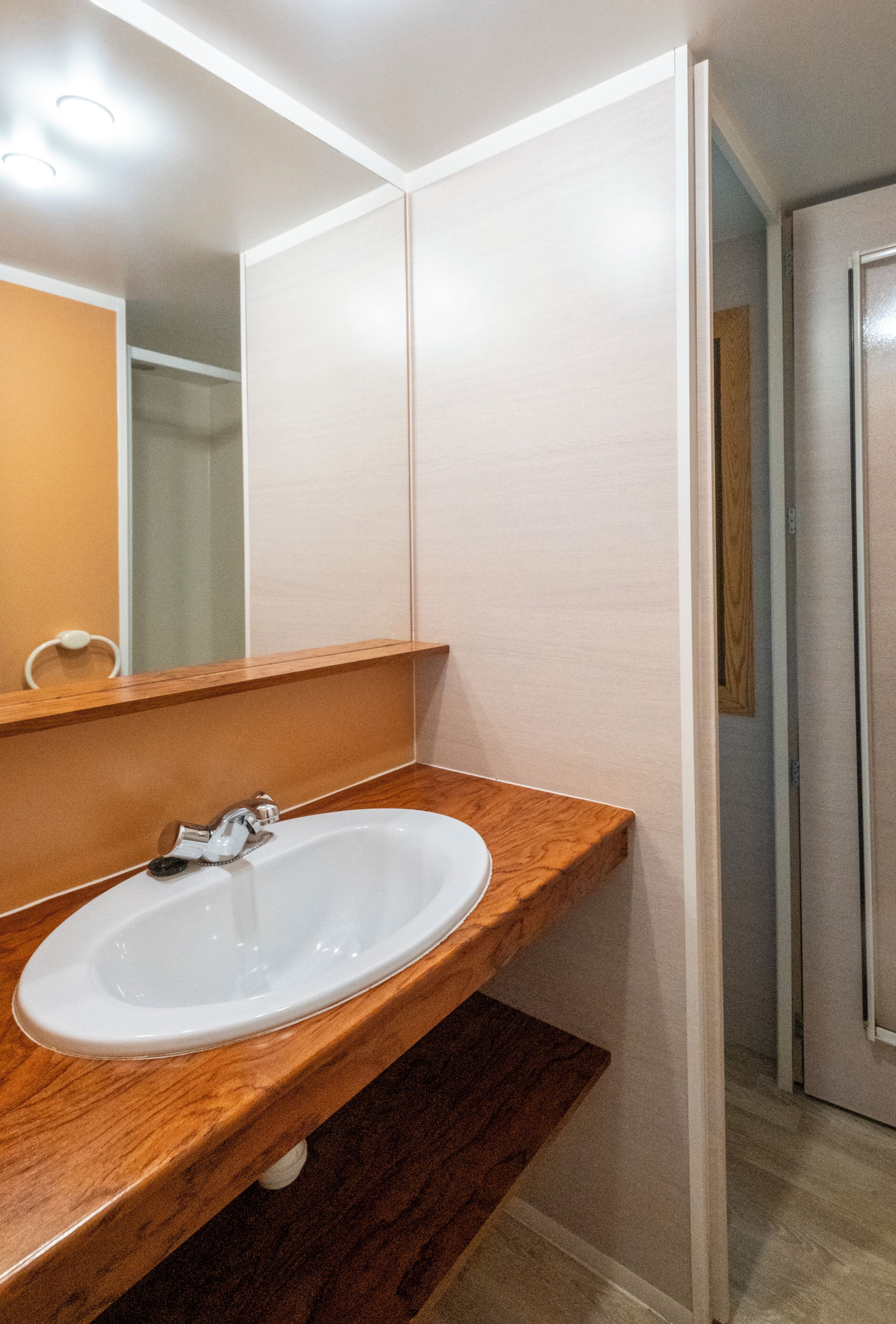 A bathroom with a wooden vanity, a white sink, and a mirror.