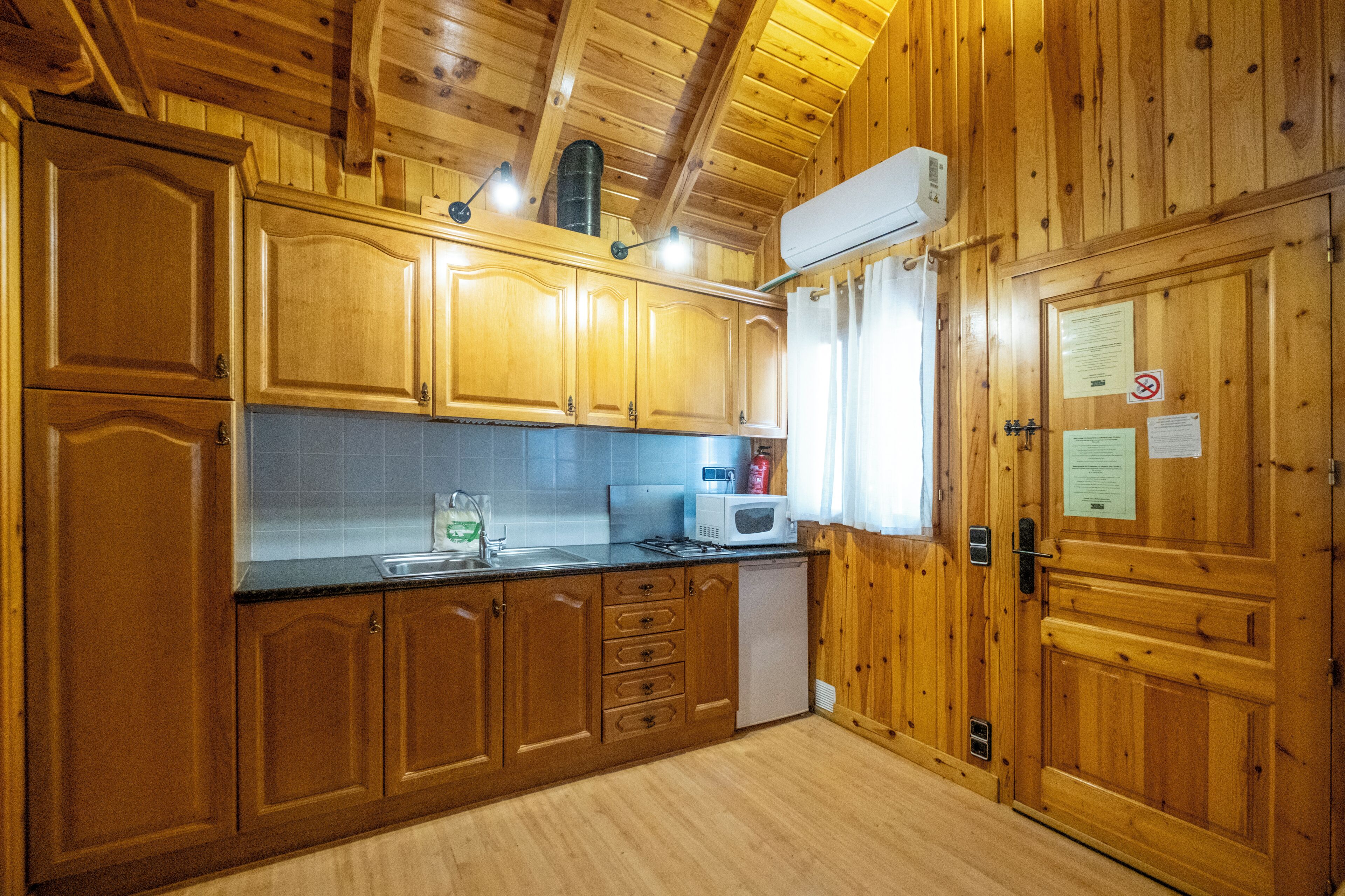 A wooden-paneled kitchen with cabinets, a microwave, and a sink.