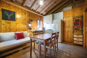 Un interior de madera con sofá, mesa de comedor, sillas, zona de cocina y microondas.