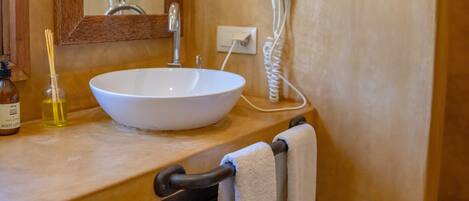 A bathroom with a large mirror, a white sink, a hairdryer, and a towel rack.