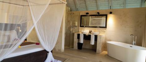 A modern bathroom with a large bathtub, a glass-enclosed shower, and a vanity with a mirror.