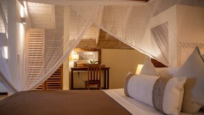 Un dormitorio con cama, almohadas, escritorio y silla.