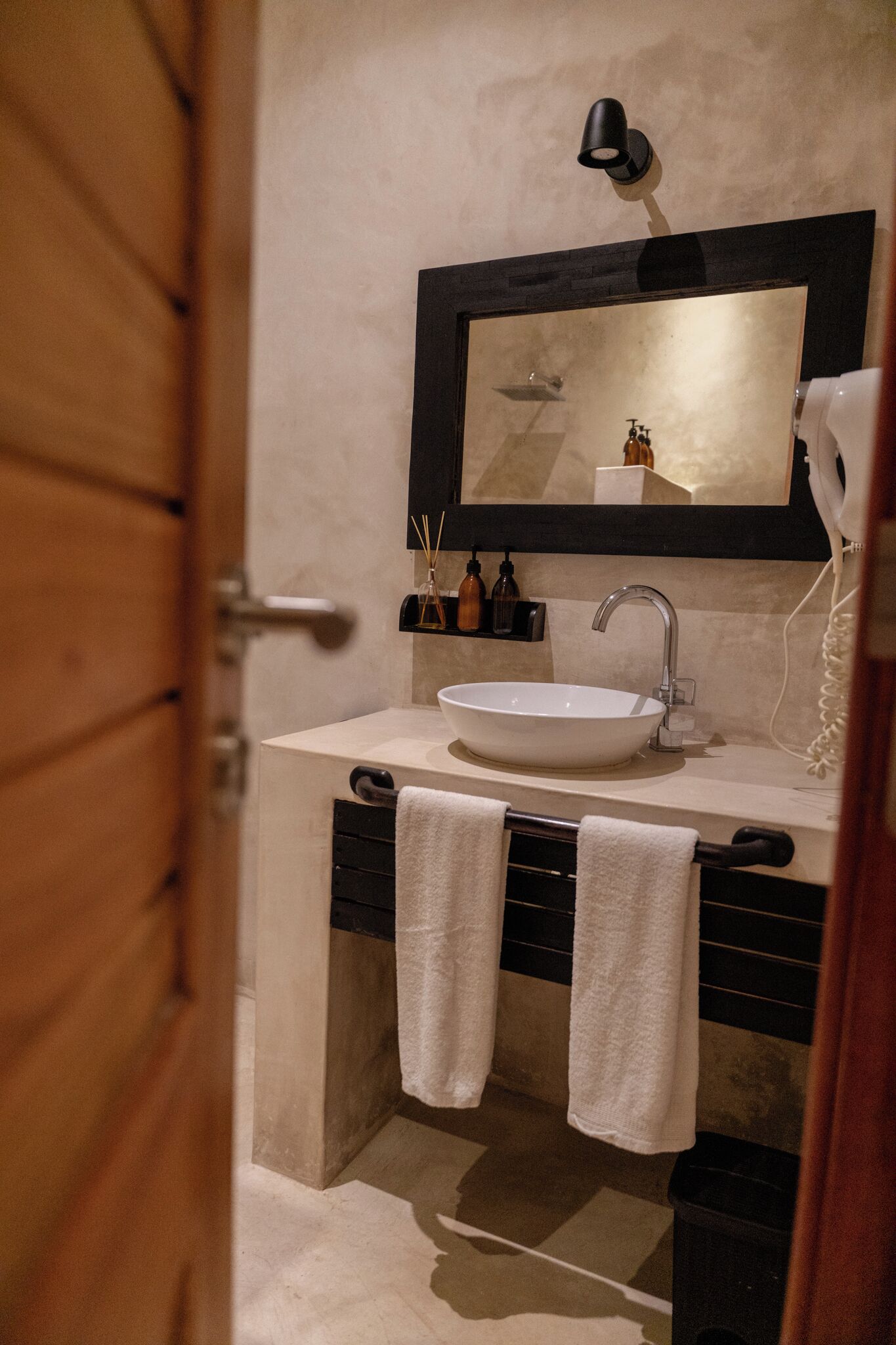 A bathroom with a white sink, a mirror, a hairdryer, and two towels hanging on a rack.