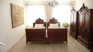 Una cama doble con estructura de madera, un candelabro y un cuadro grande en la pared.