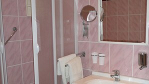 Un baño con ducha, lavamanos y espejo.
